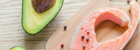 Fresh wild caught salmon and avocado HCG Phase 3 Healthy Food List with peppercorns on cutting board